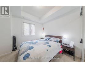 A bedroom with a bed, nightstand, and window.