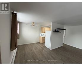 A room with a ceiling fan and a refrigerator in it.