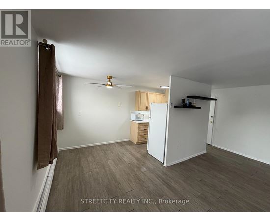 A room with a ceiling fan and a refrigerator in it.