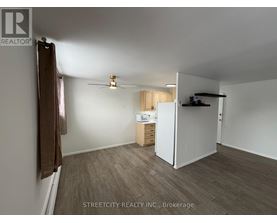 A room with a ceiling fan and a small kitchenette.