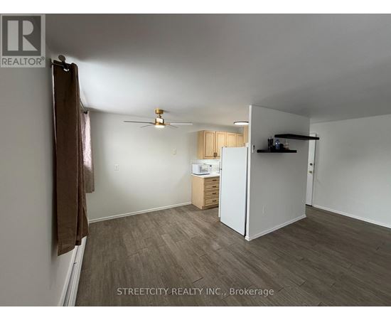 A room with a ceiling fan and a small kitchenette.