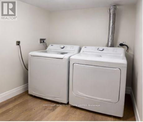 A pair of white front loading washing machines in a small room.