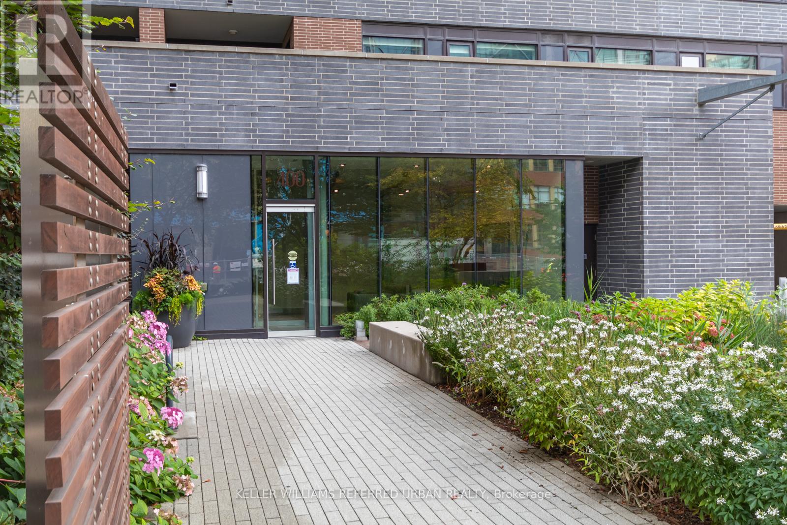 A building entrance with a glass door and a brick wall on the left.