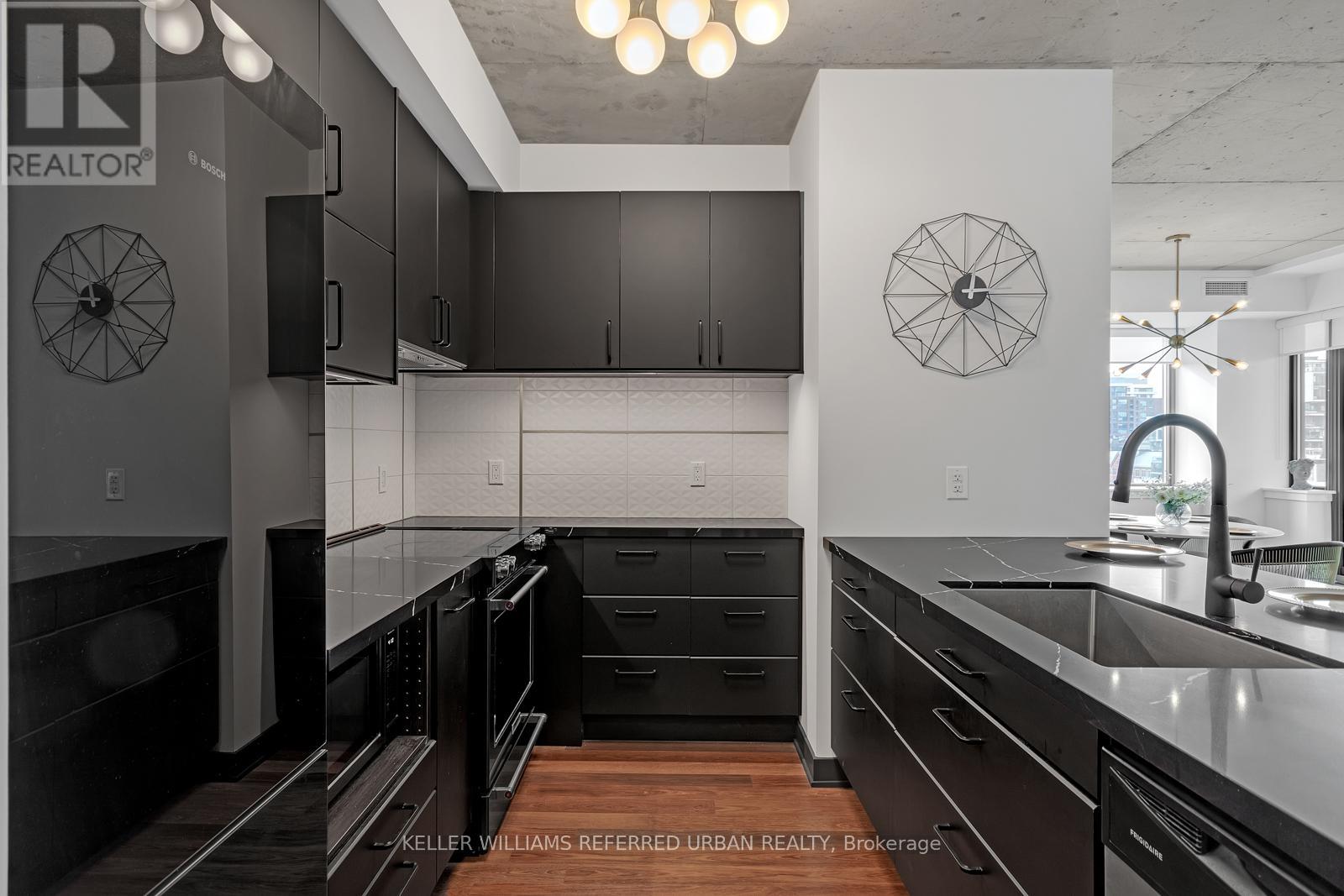 A modern kitchen with dark cabinets and a large island.