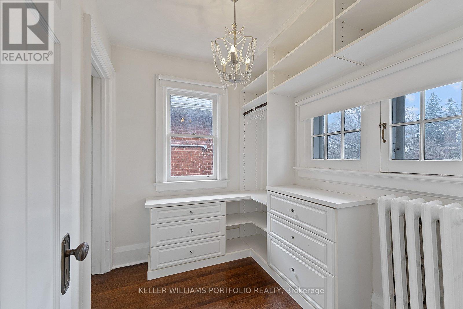 A white room with a chandelier and a window with a view of a red building.