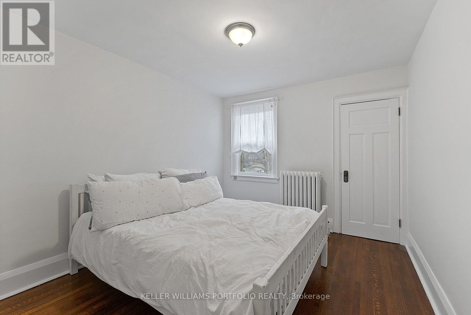 A bedroom with a white bed and a window with curtains.