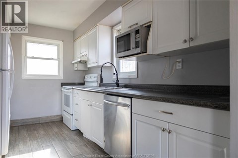A kitchen with white cabinets and a black countertop.