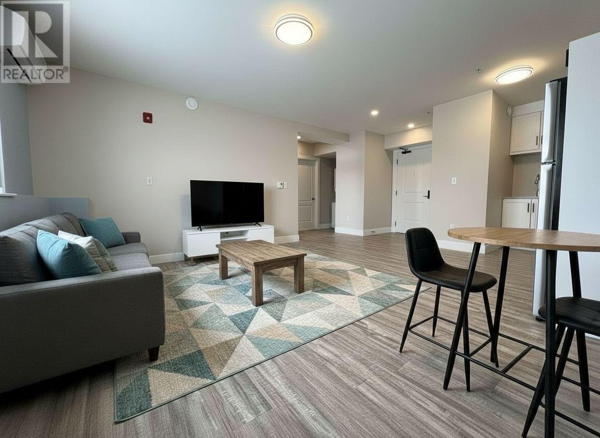A living room with a grey couch, a wooden table, and a television.