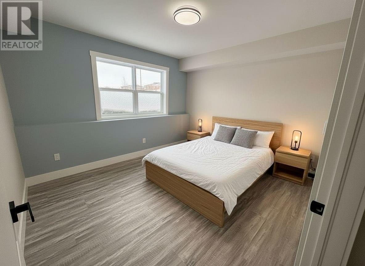 A bedroom with a bed, nightstands, and a window.