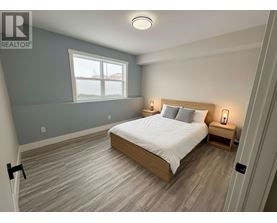 A bedroom with a bed, nightstands, and a window.