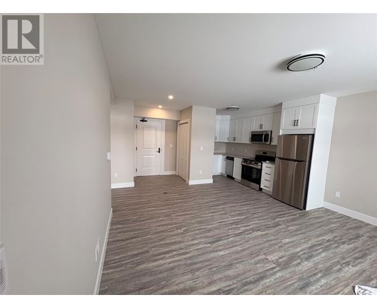 A spacious living area with a kitchen in the background.