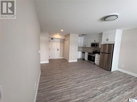 A spacious living area with a kitchen in the background.