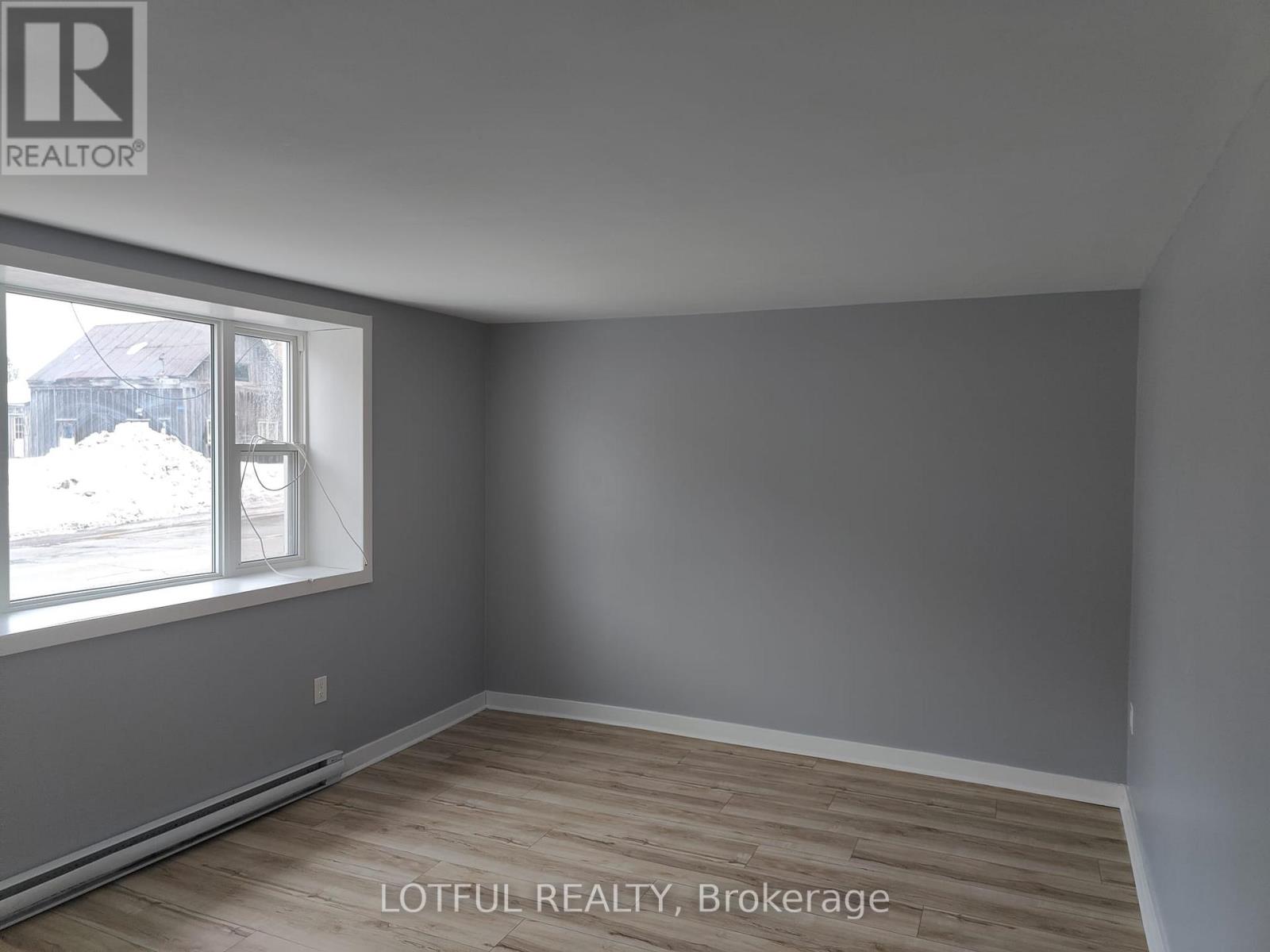 A room with a window and wooden flooring.