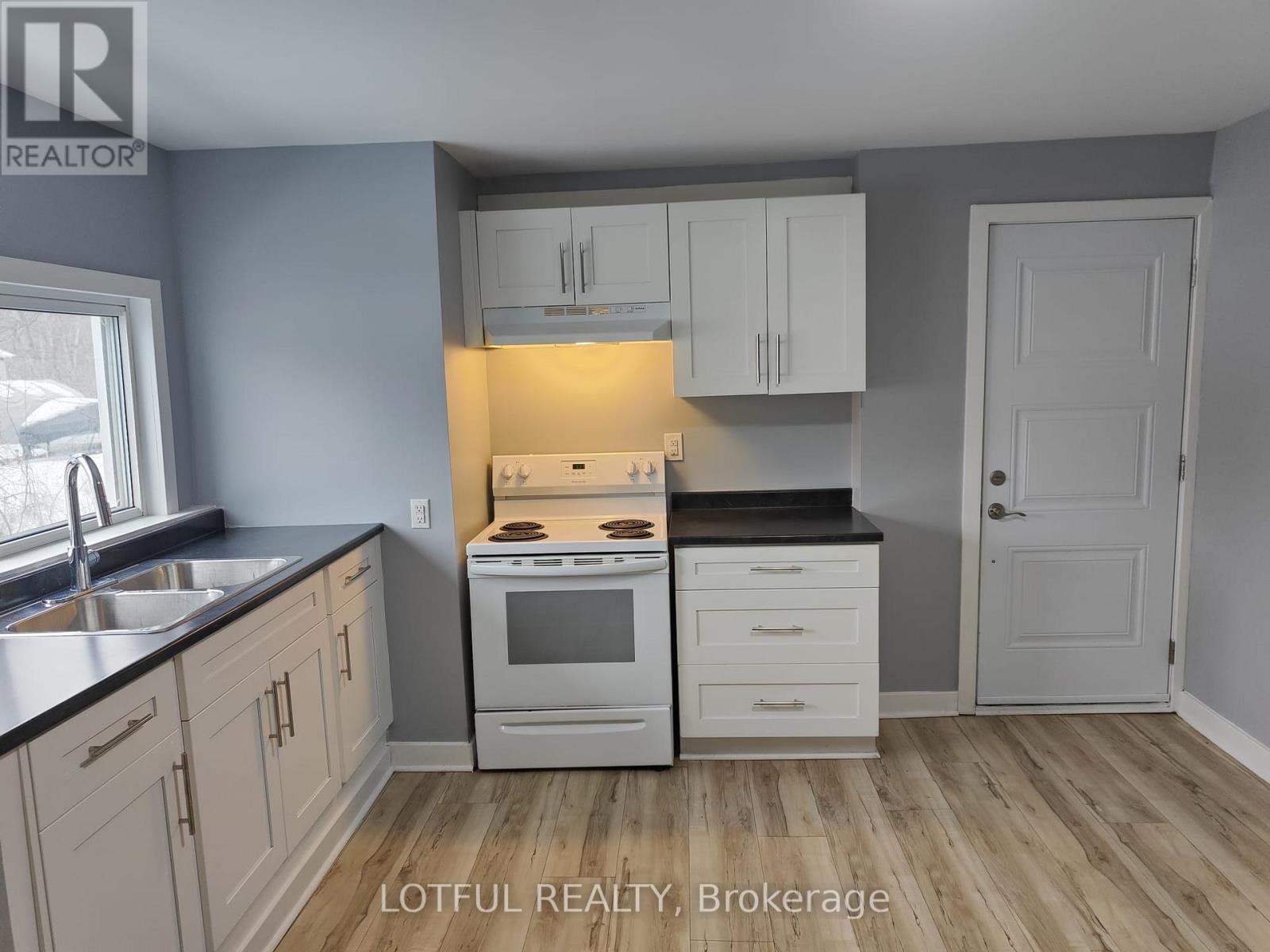 A kitchen with white cabinets and a black countertop.
