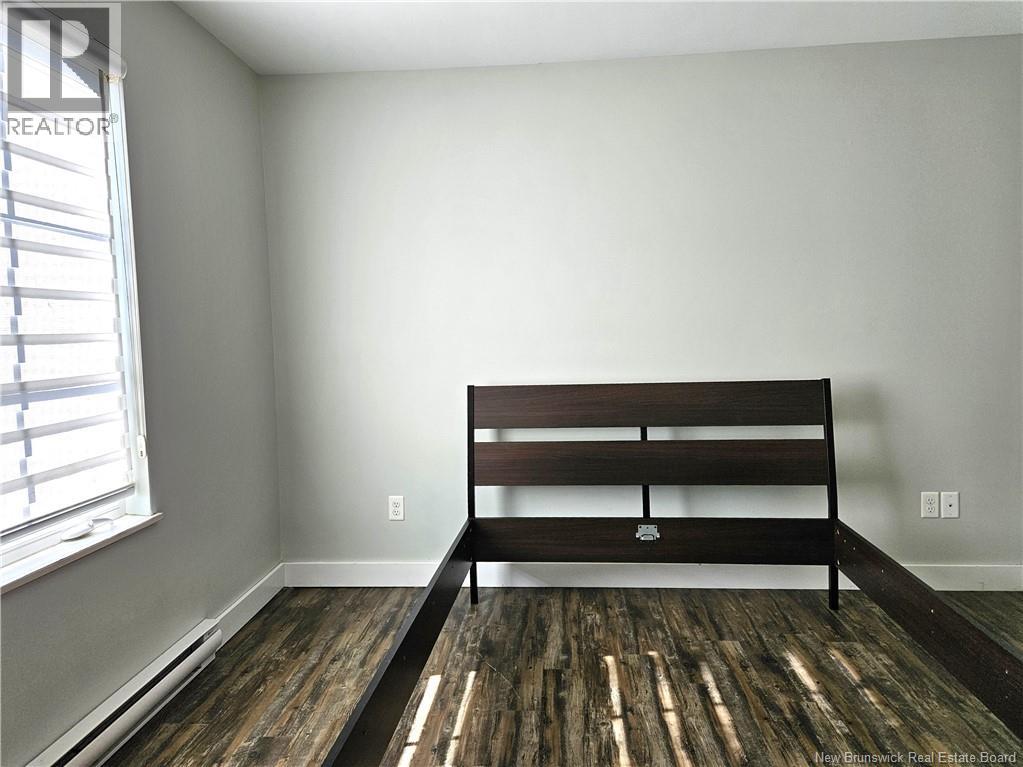 A bedroom with a bed and wooden flooring.
