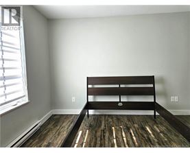 A bedroom with a bed and wooden flooring.
