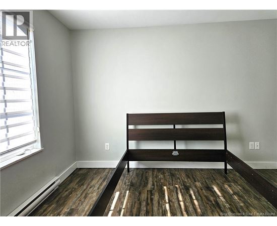 A bedroom with a bed and wooden flooring.