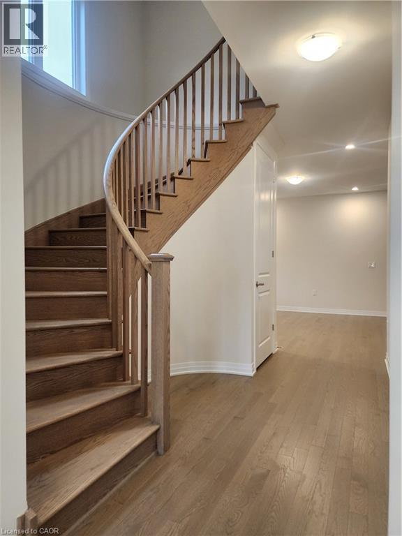 A wooden staircase with a black railing leads up to a white door.