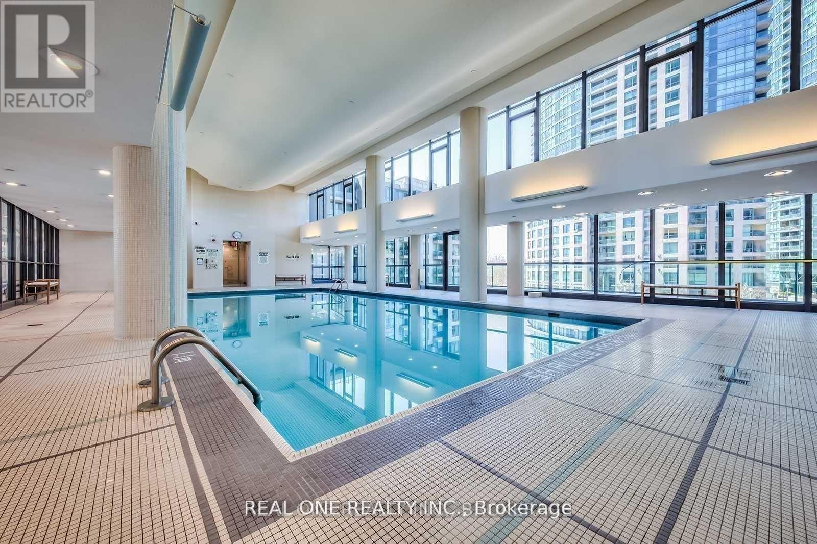 A large indoor swimming pool with a tiled floor and a glass wall.
