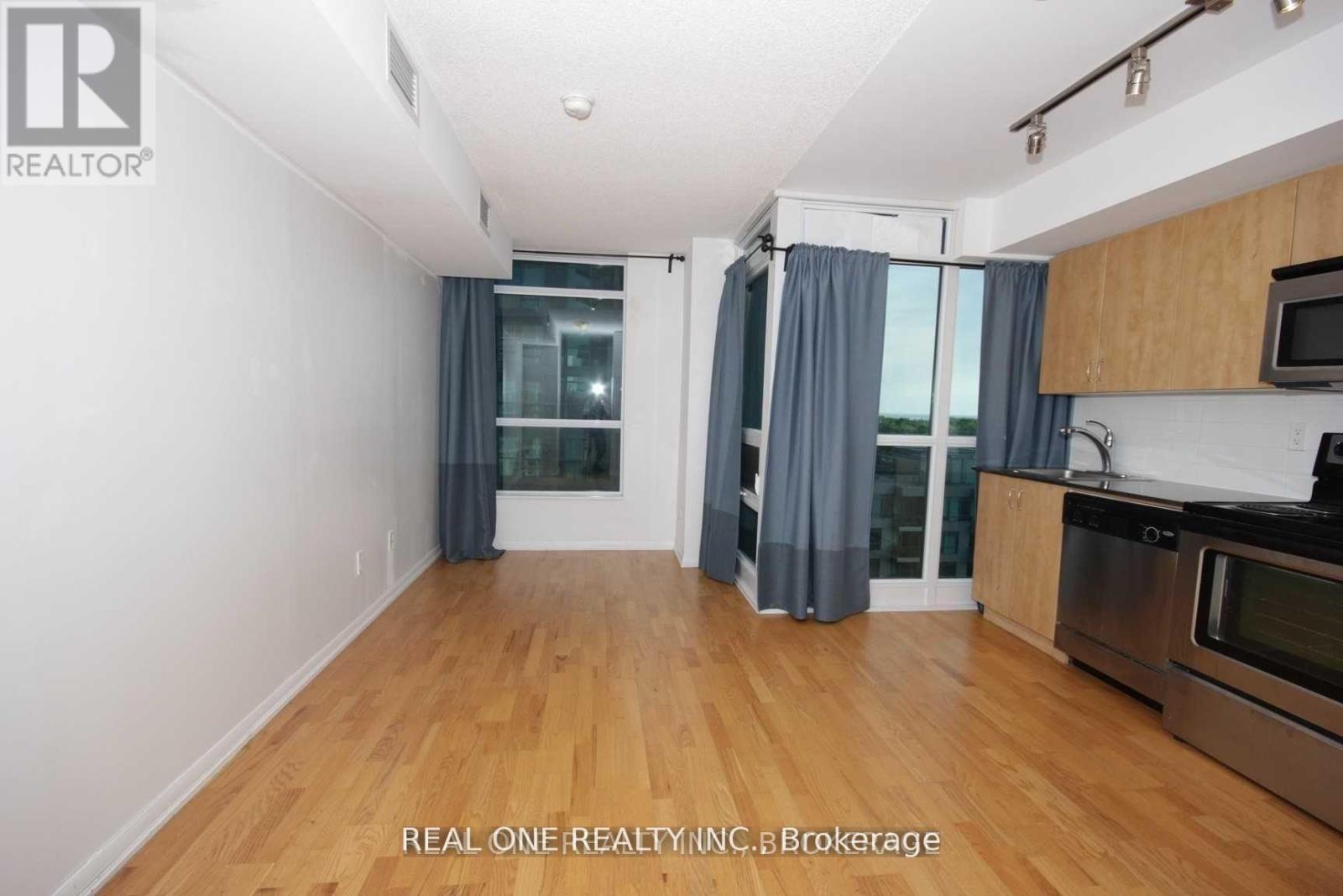 A spacious kitchen and living room with wooden floors and white walls.
