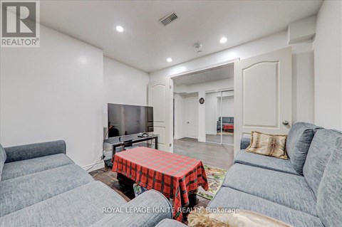 A living room with a grey couch and a red and black checkered tablecloth on the table.