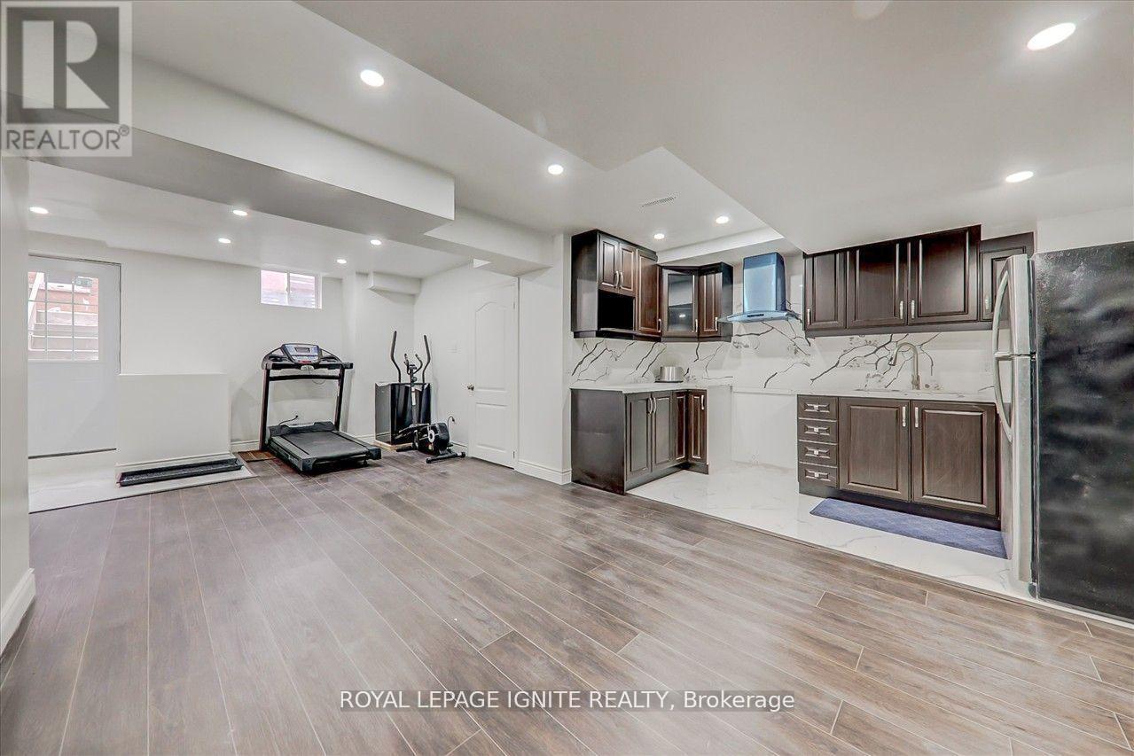 A spacious room with wooden flooring and a variety of furniture and appliances.