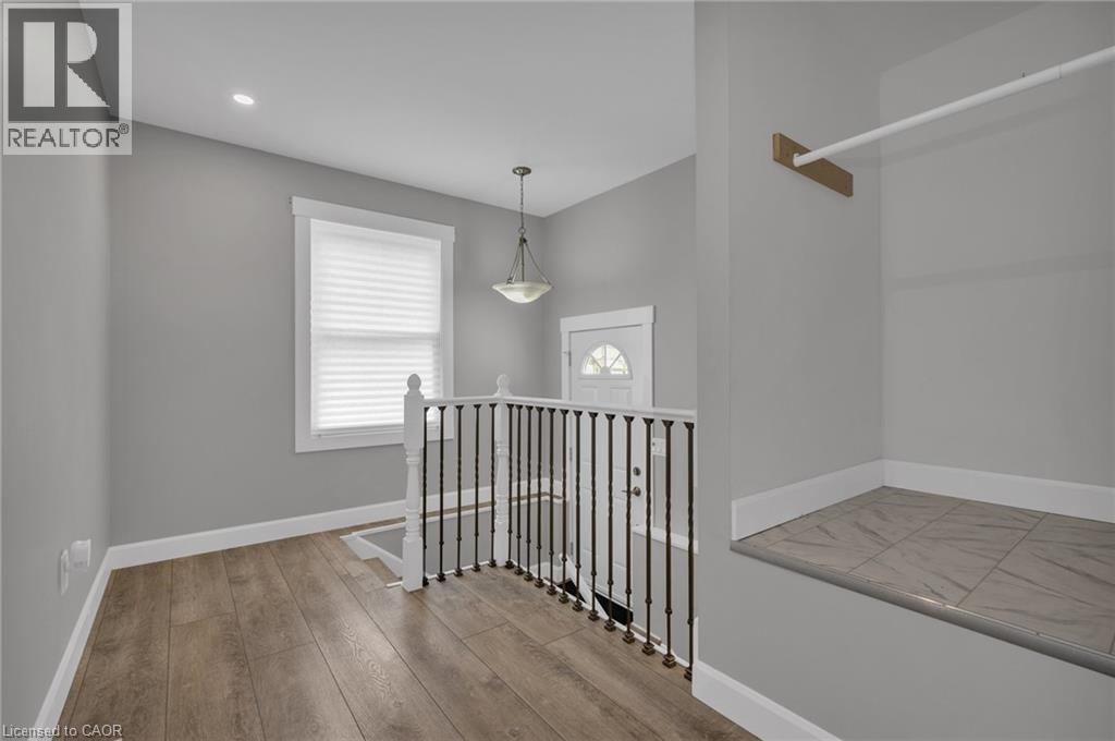 A well-lit, spacious room with a window, a chandelier, and a wooden floor.