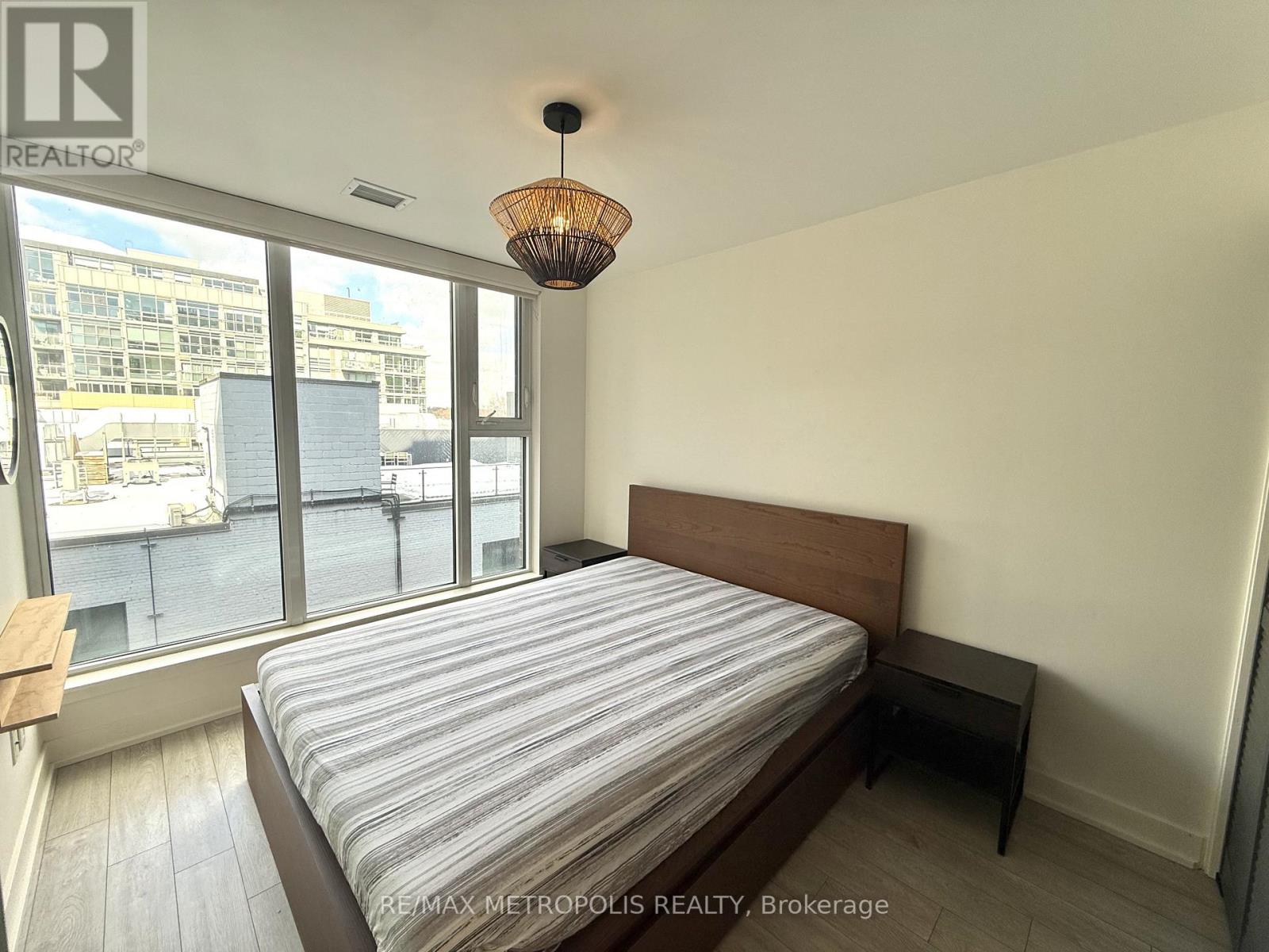 A bedroom with a large bed and a window overlooking a cityscape.