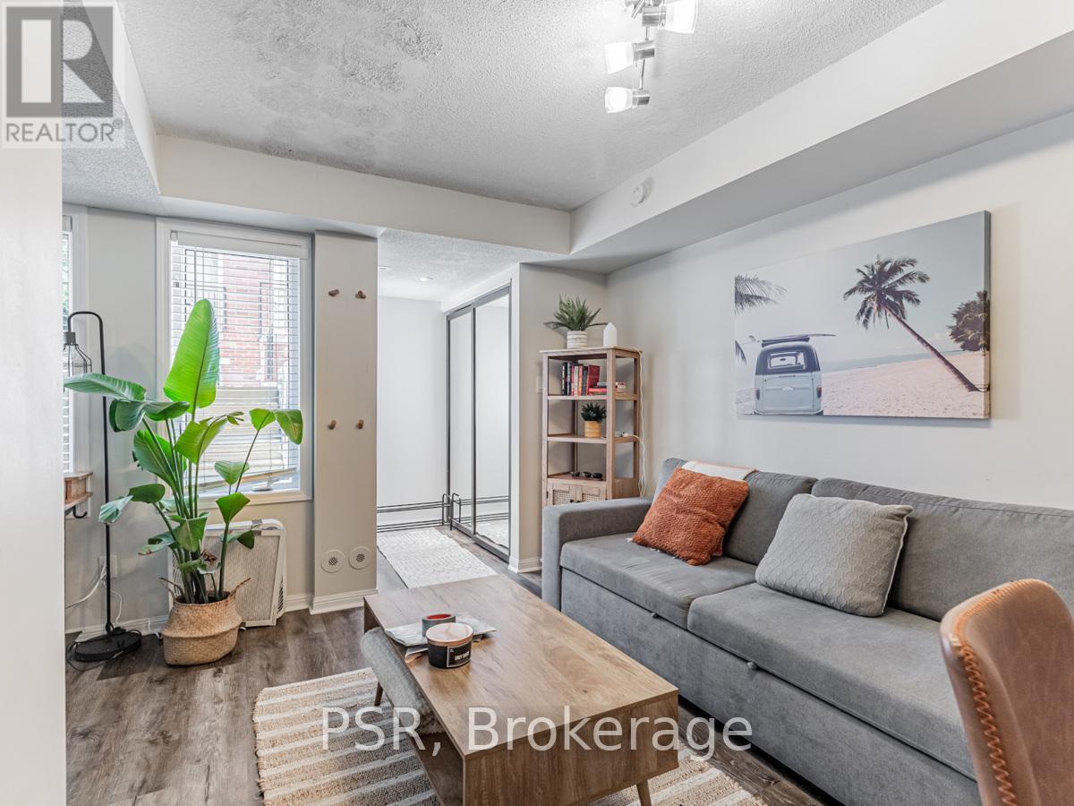 A living room with a grey couch, a coffee table, and a painting on the wall.