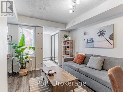 A living room with a grey couch, a coffee table, and a painting on the wall.