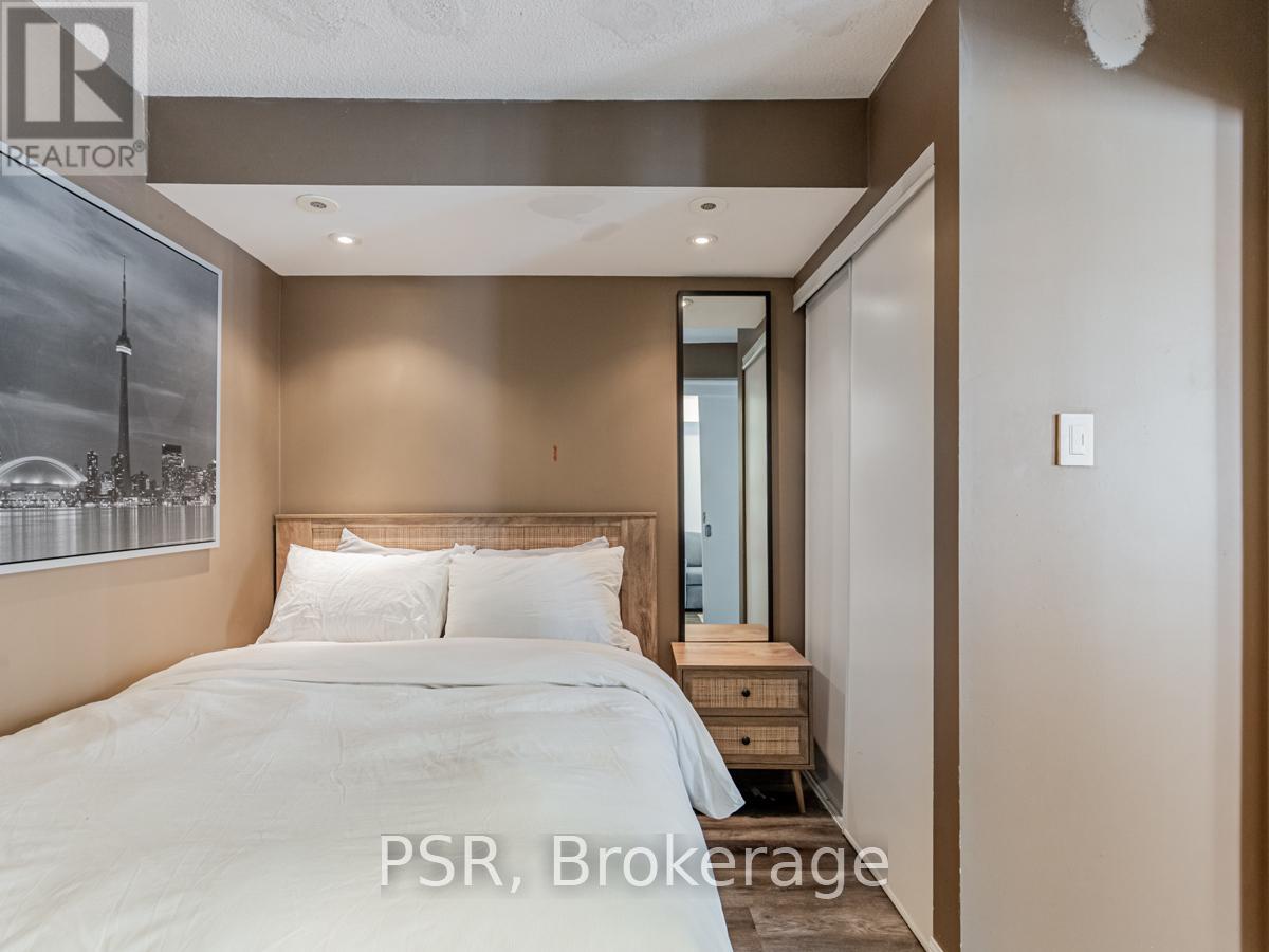 A bedroom with a large bed and a framed picture of a city skyline on the wall.