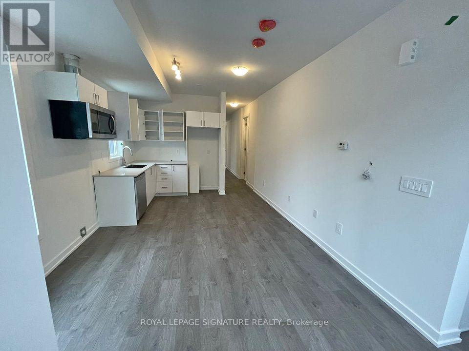 A well-lit, spacious room with a kitchenette and a doorway leading to another room.