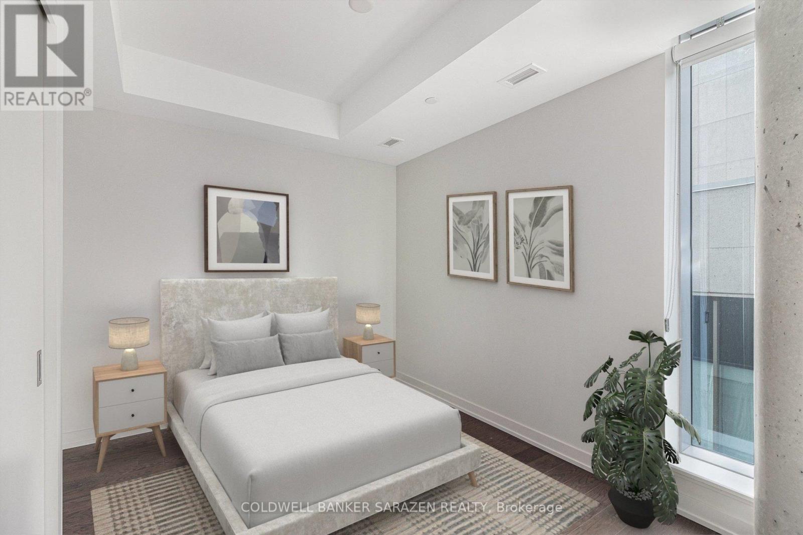 A bedroom with a large bed, two nightstands with lamps, and a potted plant.