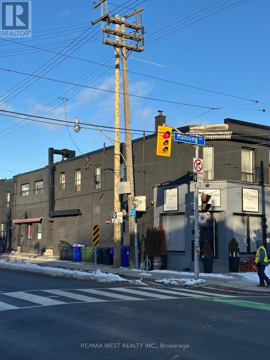 A street scene with a traffic light and a building with a sign that says "RE/MAX WEST REALTY INC., Brokerage".