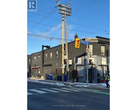 A street scene with a traffic light and a building with a sign that says "RE/MAX WEST REALTY INC., Brokerage".