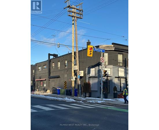 A street scene with a traffic light and a building with a sign that says "RE/MAX WEST REALTY INC., Brokerage".