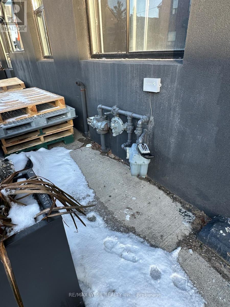 A dirty outdoor area with a pipe and a white bucket.