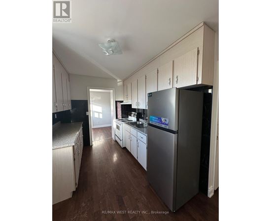 A kitchen with a refrigerator, cabinets, and a stove top oven.