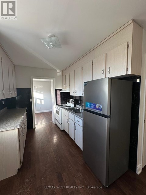 A kitchen with a refrigerator, cabinets, and a stove top oven.