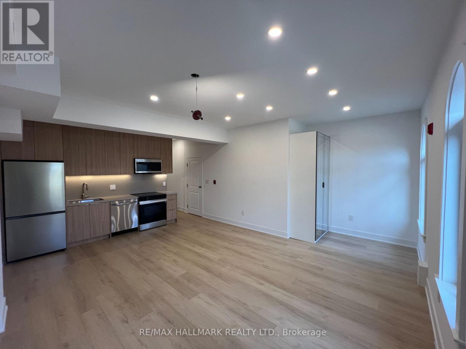 A spacious kitchen with wooden floors and a refrigerator.