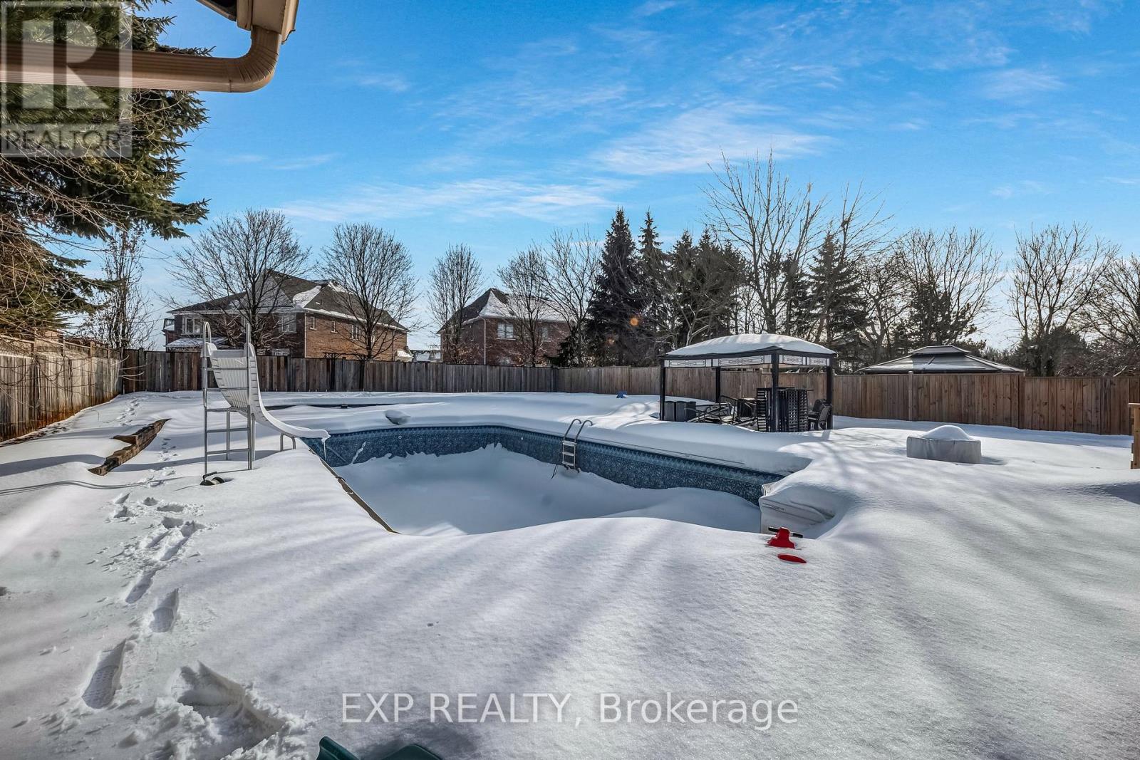A snow-covered backyard with a pool and a slide.