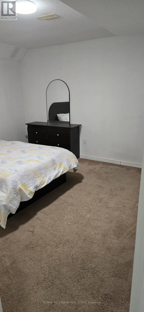 A bedroom with a bed, dresser, and carpet.