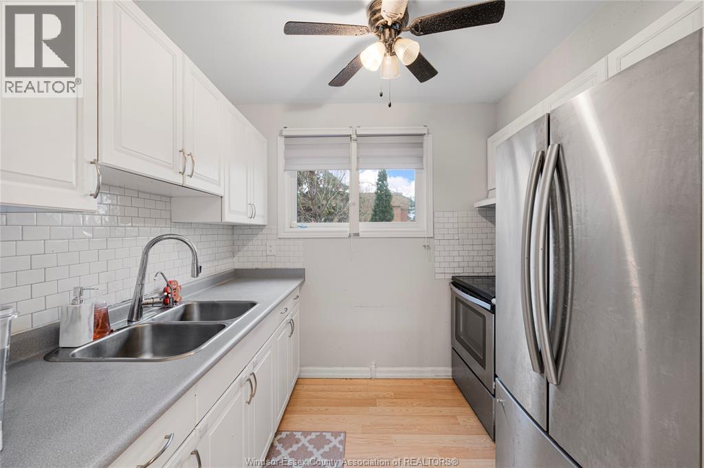 A kitchen with a stainless steel refrigerator and a ceiling fan.