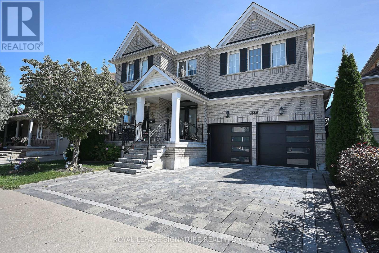 A large, two-story house with a driveway in front.