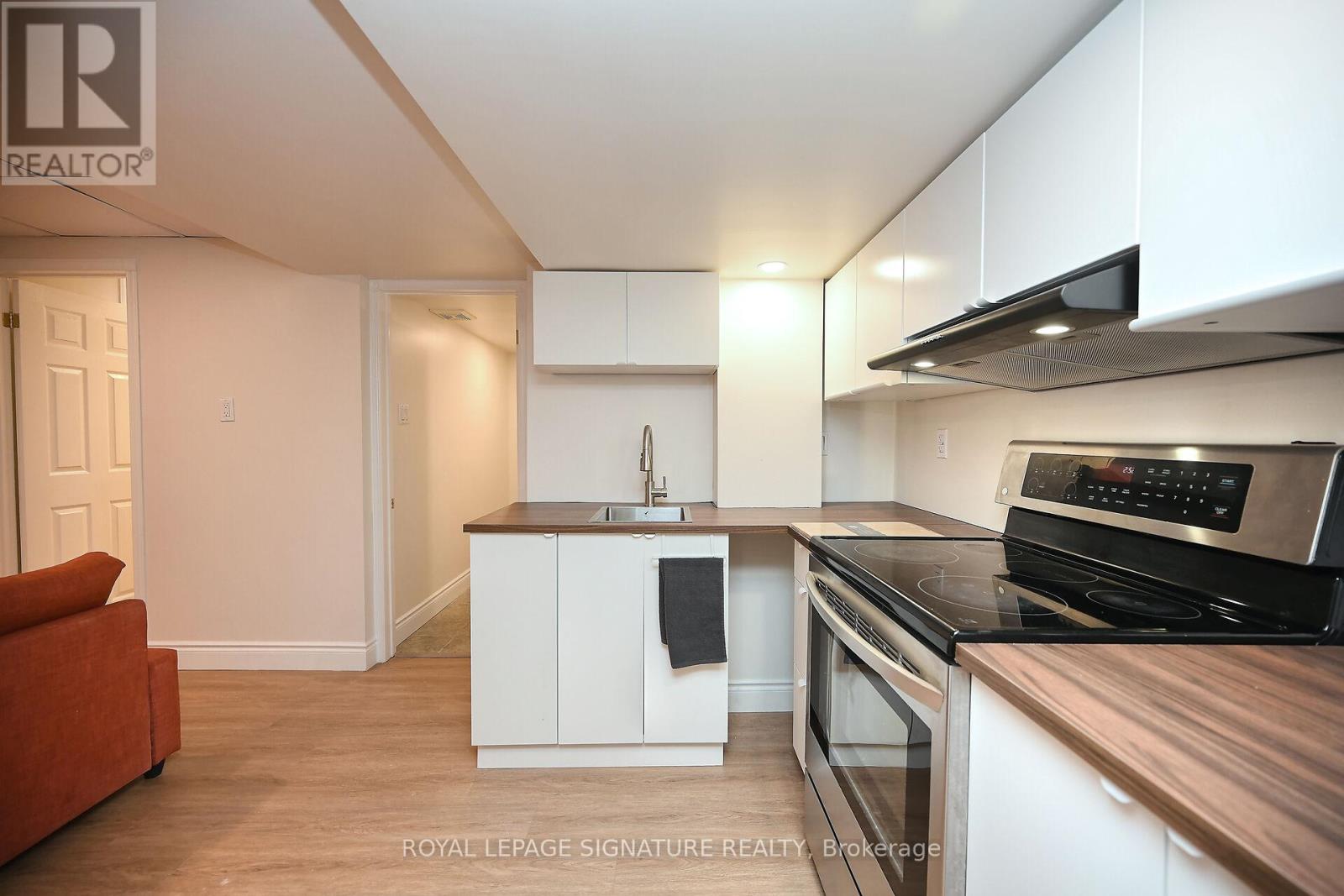 A modern kitchen with white cabinets and a wooden countertop.