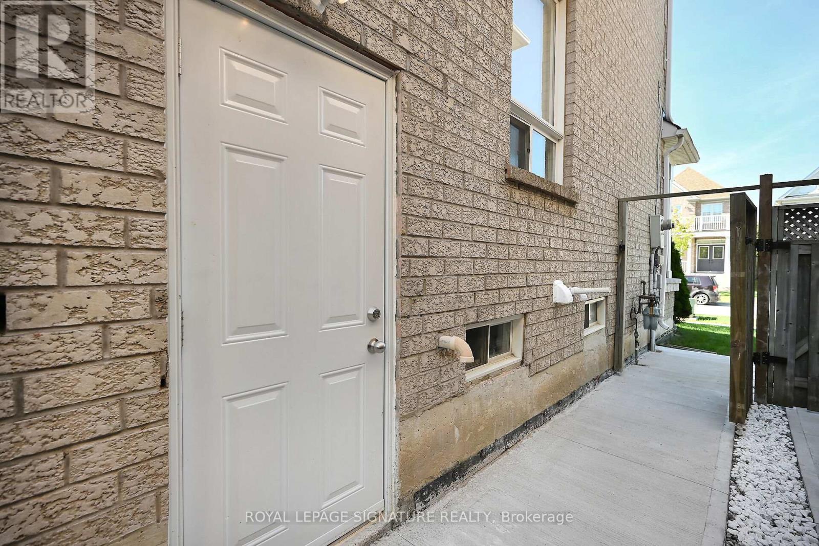 A white door is on the left side of a brick building.