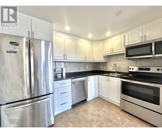 A kitchen with a refrigerator, microwave, oven, and sink.