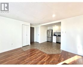 A kitchen with white walls and wooden floors.