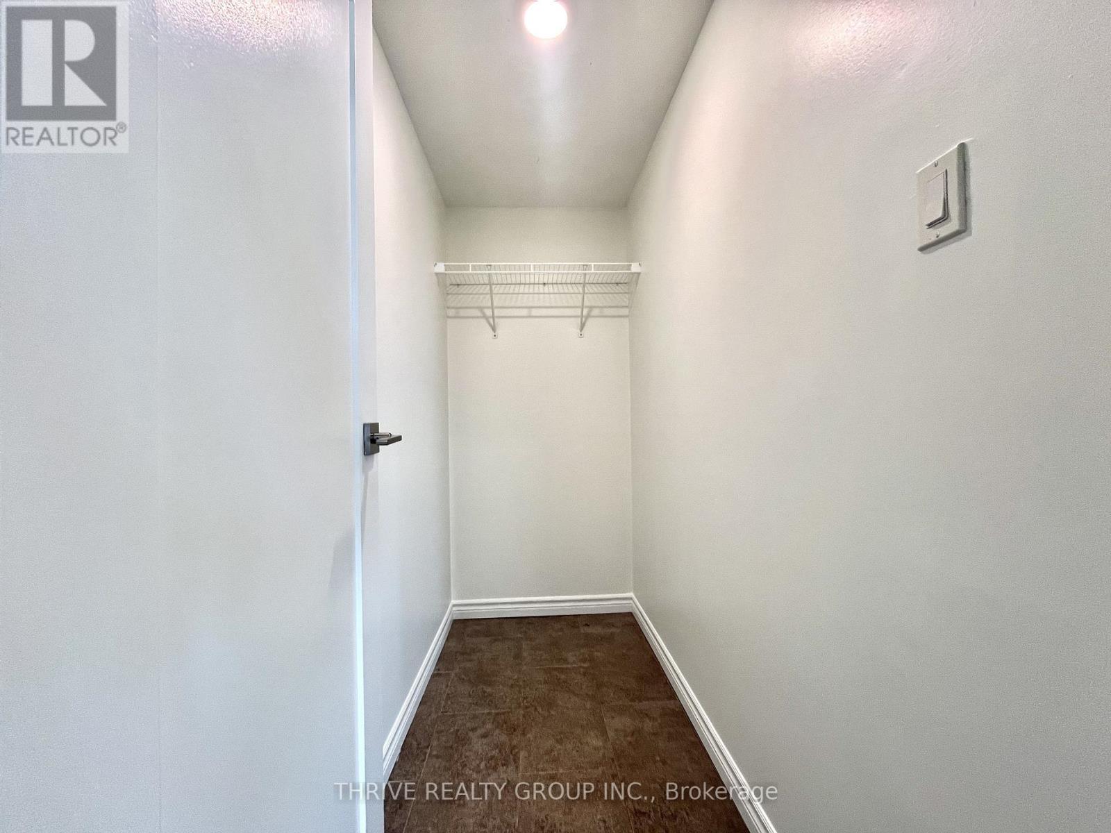 A hallway with a door on the left and a light switch on the wall.