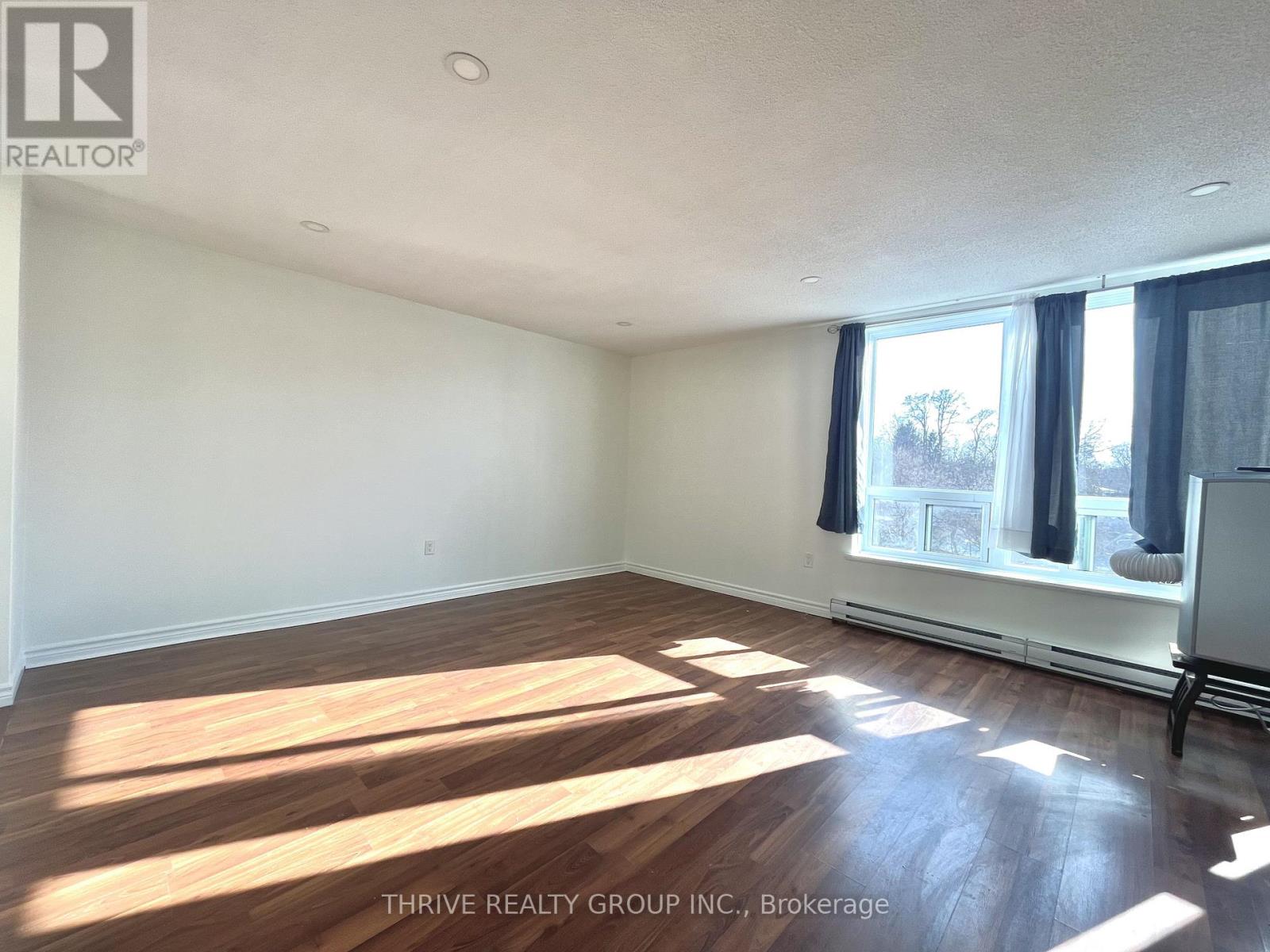 A room with wooden flooring and a window with curtains.